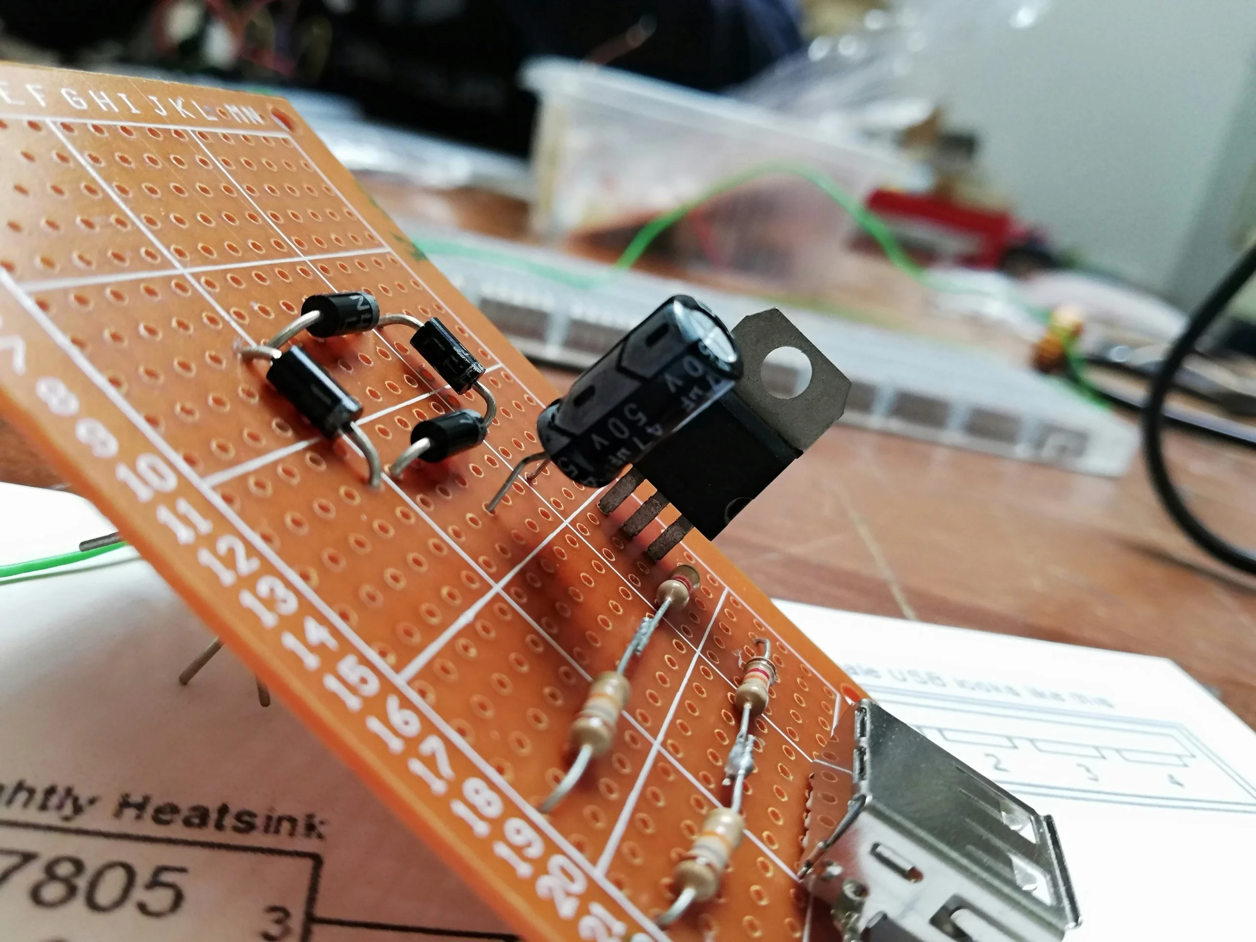 Lochplatine (Perfboard) mit Widerständen, Drahtverbindungen und einem Elektrolytkondensator in einem Elektronikprojekt